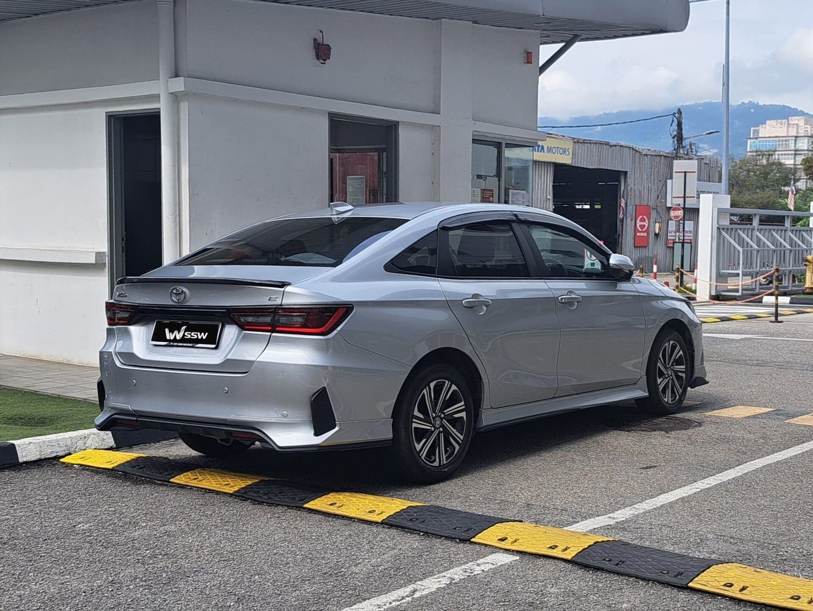 Toyota Vios 1.5 E sedan in silver, rear three-quarter view parked beside a speed bump in George Town, Penang, Malaysia, in daylight